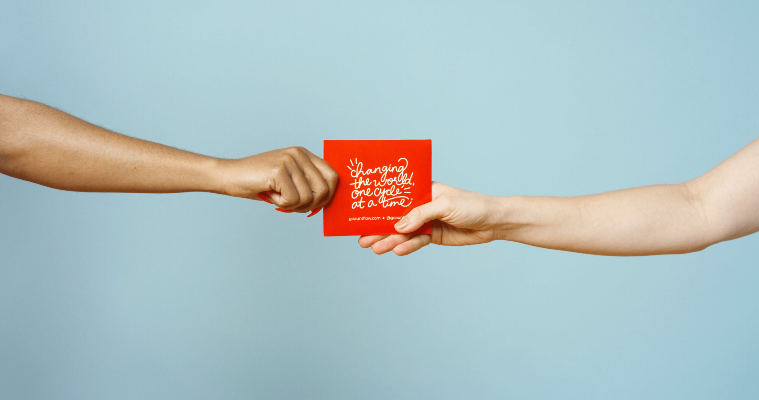 Two hands exchange a red card against a light blue background.