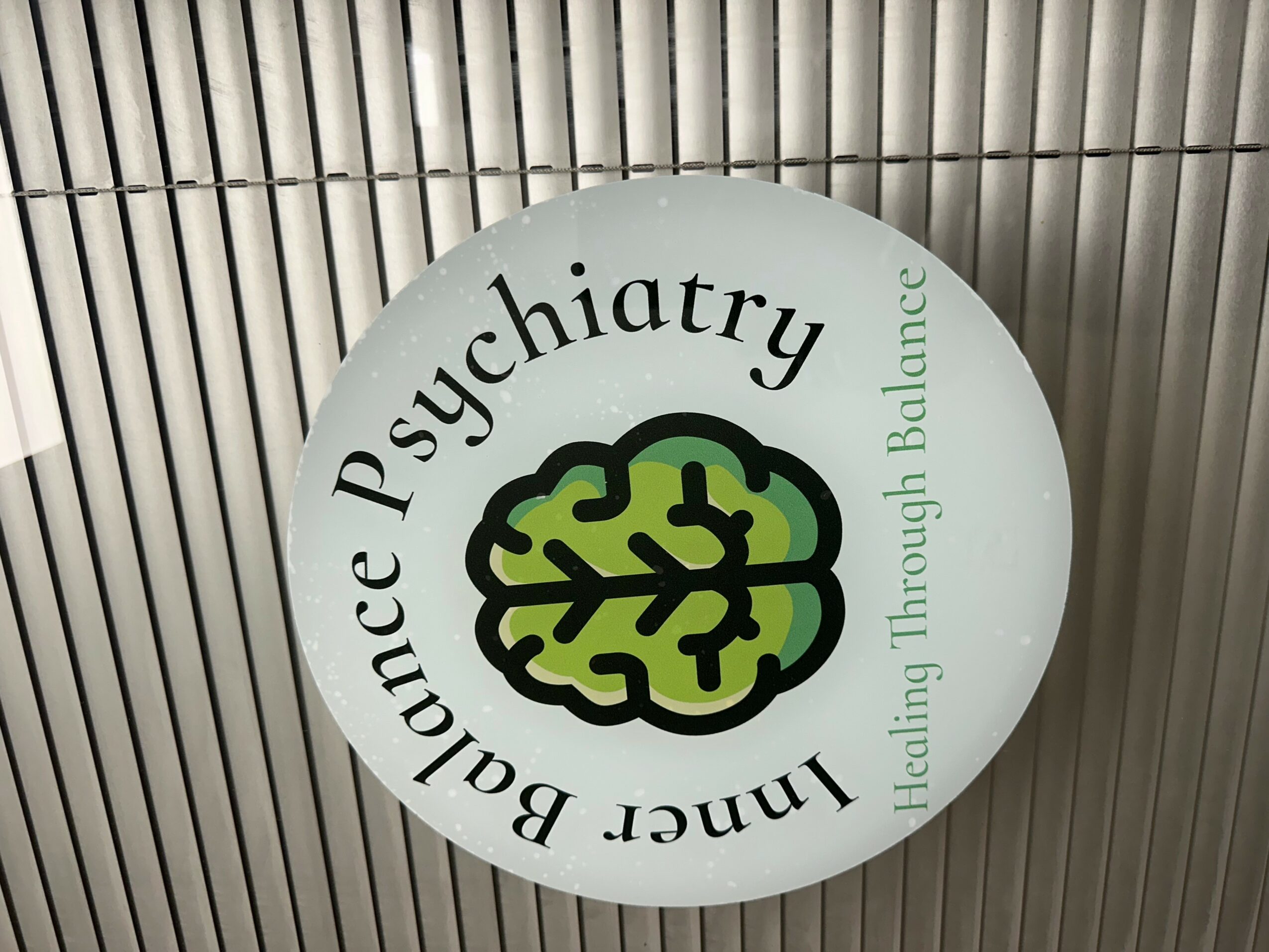 Illuminated circular sign with a green brain illustration and text about mental balance and psychiatry.