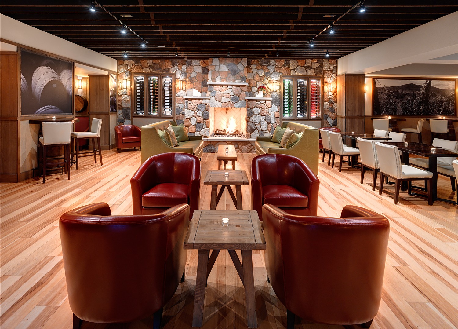 Elegant lounge with leather chairs, wooden tables, a stone fireplace, and a mix of modern and rustic decor.