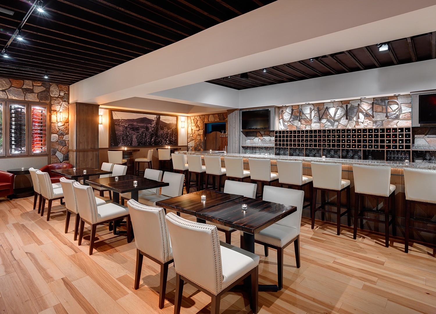 Elegant restaurant interior with tables, chairs, bar area, and warm lighting, featuring wooden floors and modern decor.