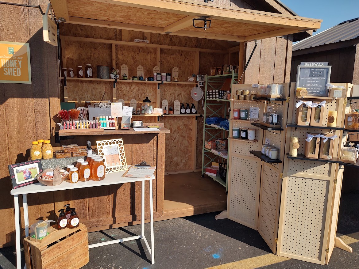 Small wooden shop with shelves of jars, bottles, and products, and a table displaying items for sale.