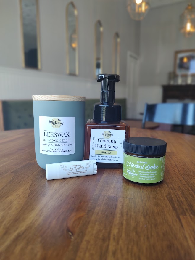 Three personal care products on a wooden table in a room with white walls and blue chairs.