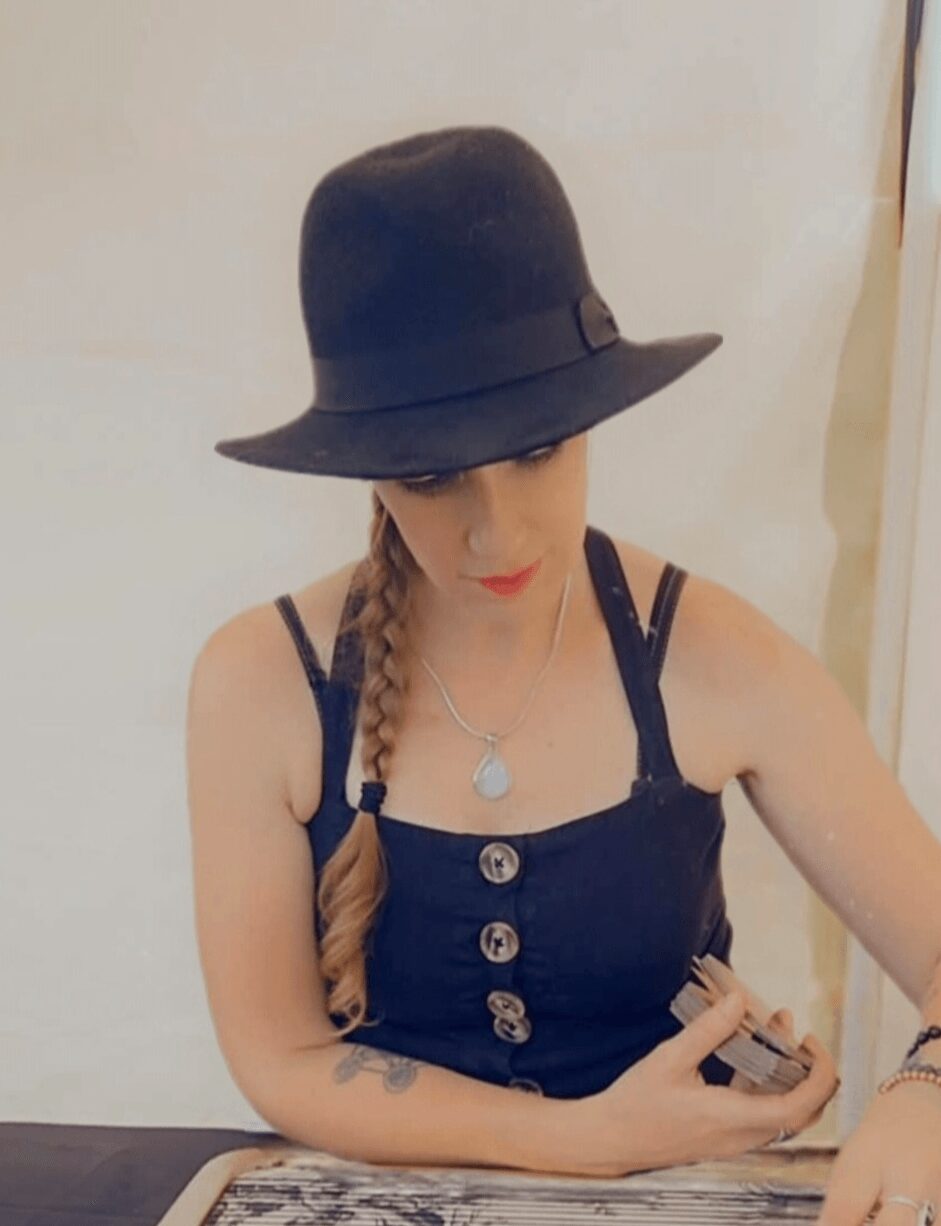 Woman with braided hair wearing a black hat and navy blue dress, looking at her phone.