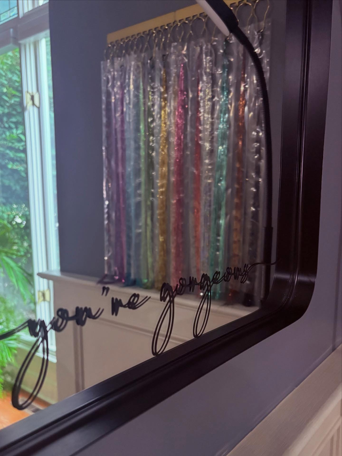 Window with colorful, shiny curtain behind glass, with handwritten message on the window reading 'you me just you'.