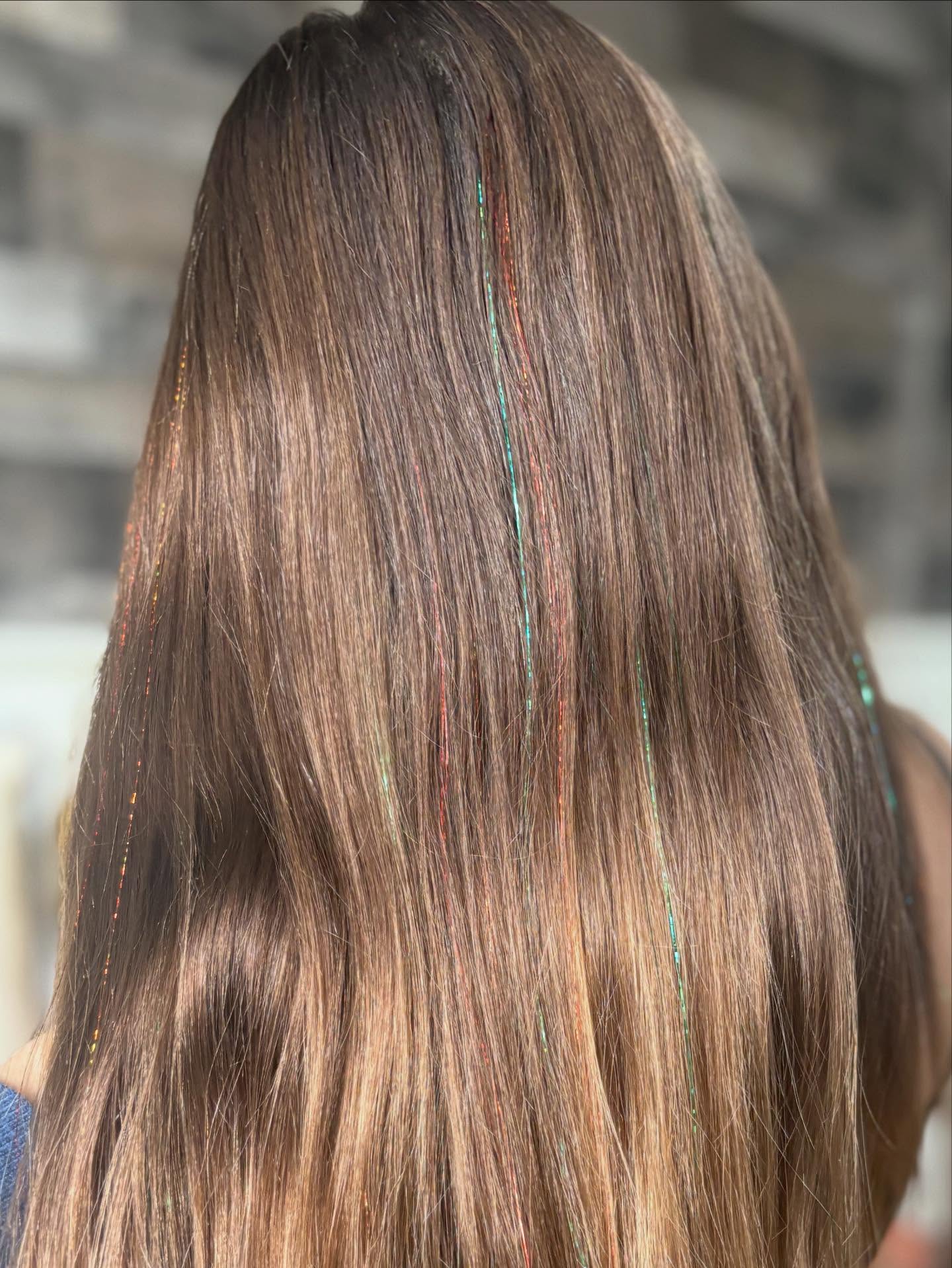 Back of a person with long, straight, brown hair with subtle highlights.