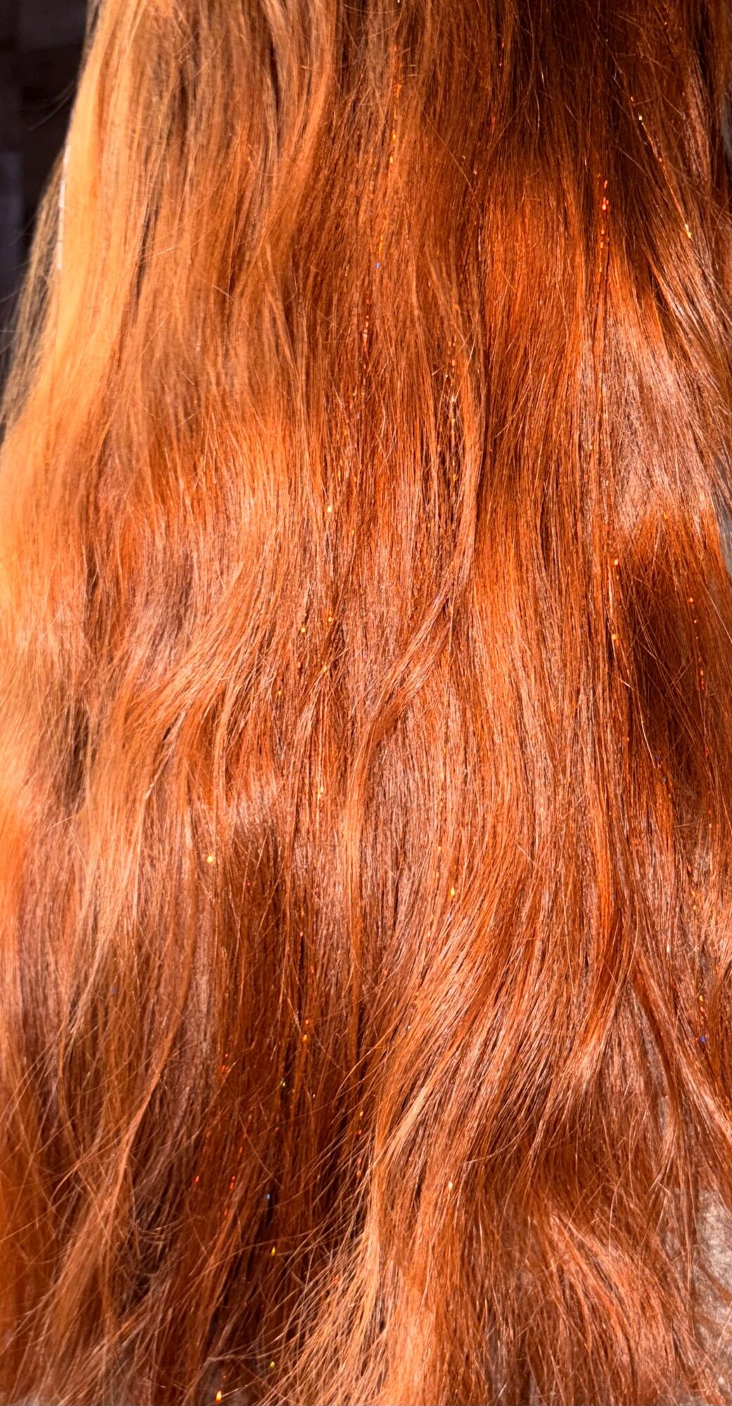 Close-up of long, wavy, reddish-brown hair with natural shine.