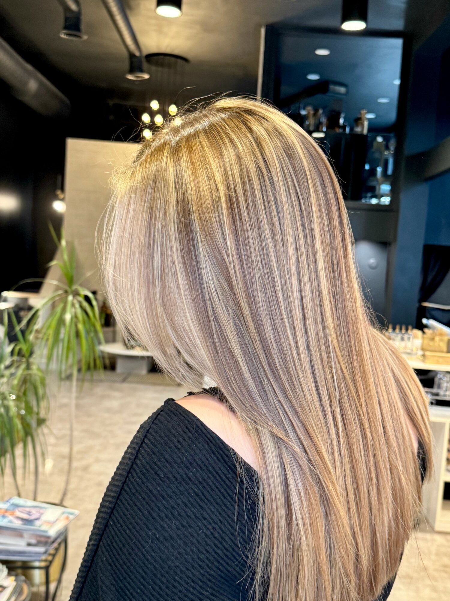Back of a woman with long, straight, blonde hair in a salon setting.