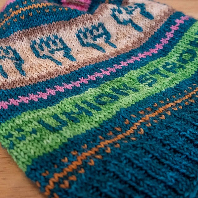 Close-up of colorful knitted fabric with various patterns and colors including blue, green, pink, and beige.