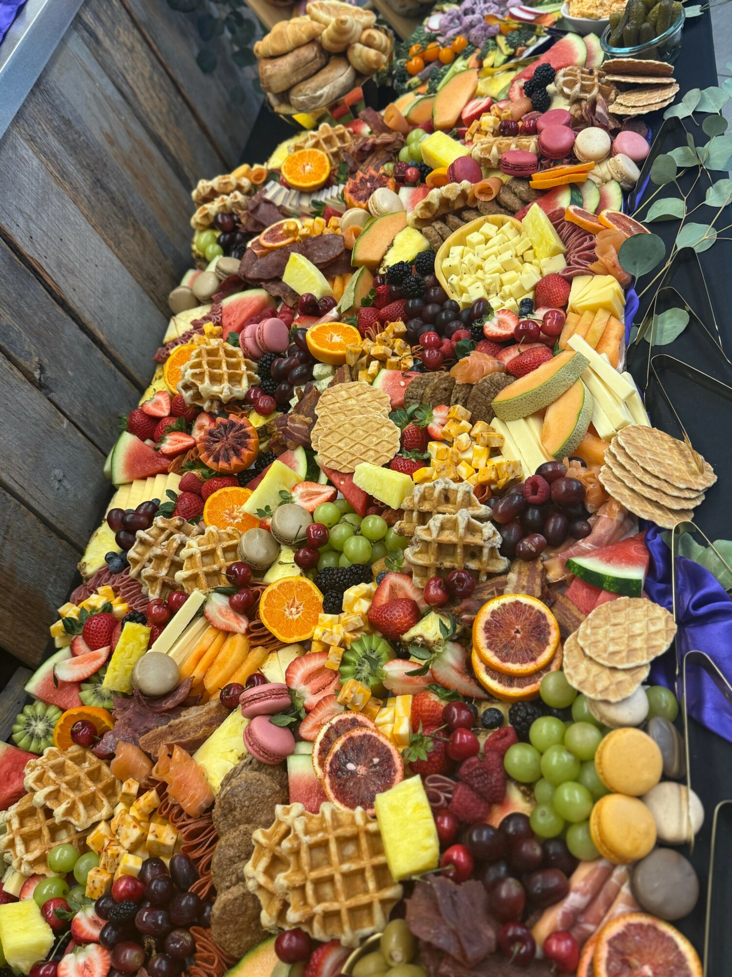 Large table filled with various colorful fruits, desserts, and snacks, arranged in a long display.