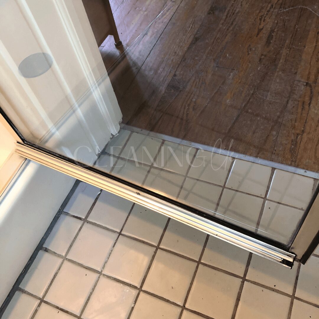 View of a sliding glass door with a tiled floor inside and a wooden floor outside.