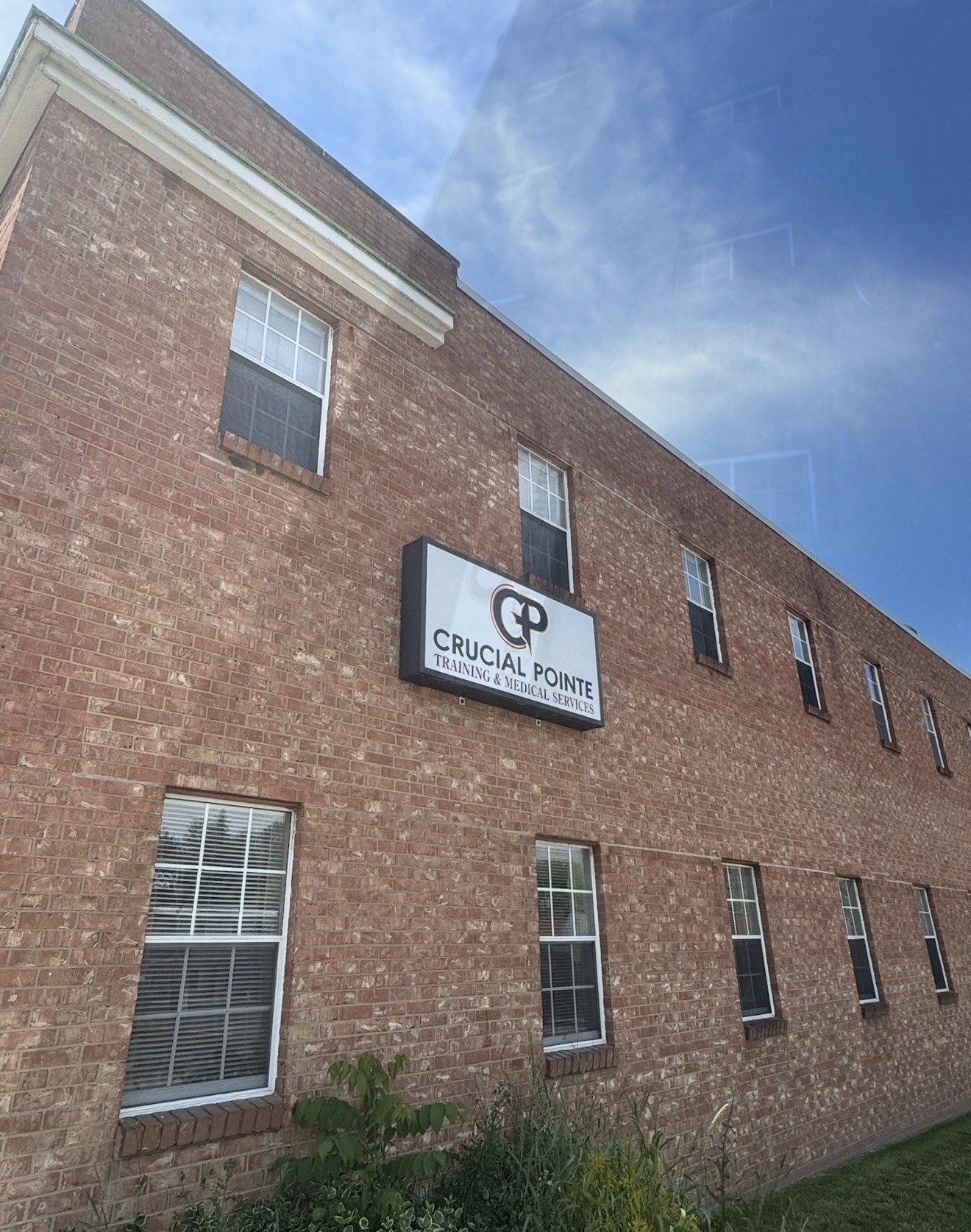 Brick building with multiple windows and a sign reading 'CRUCIAL POINTE' under a blue sky.