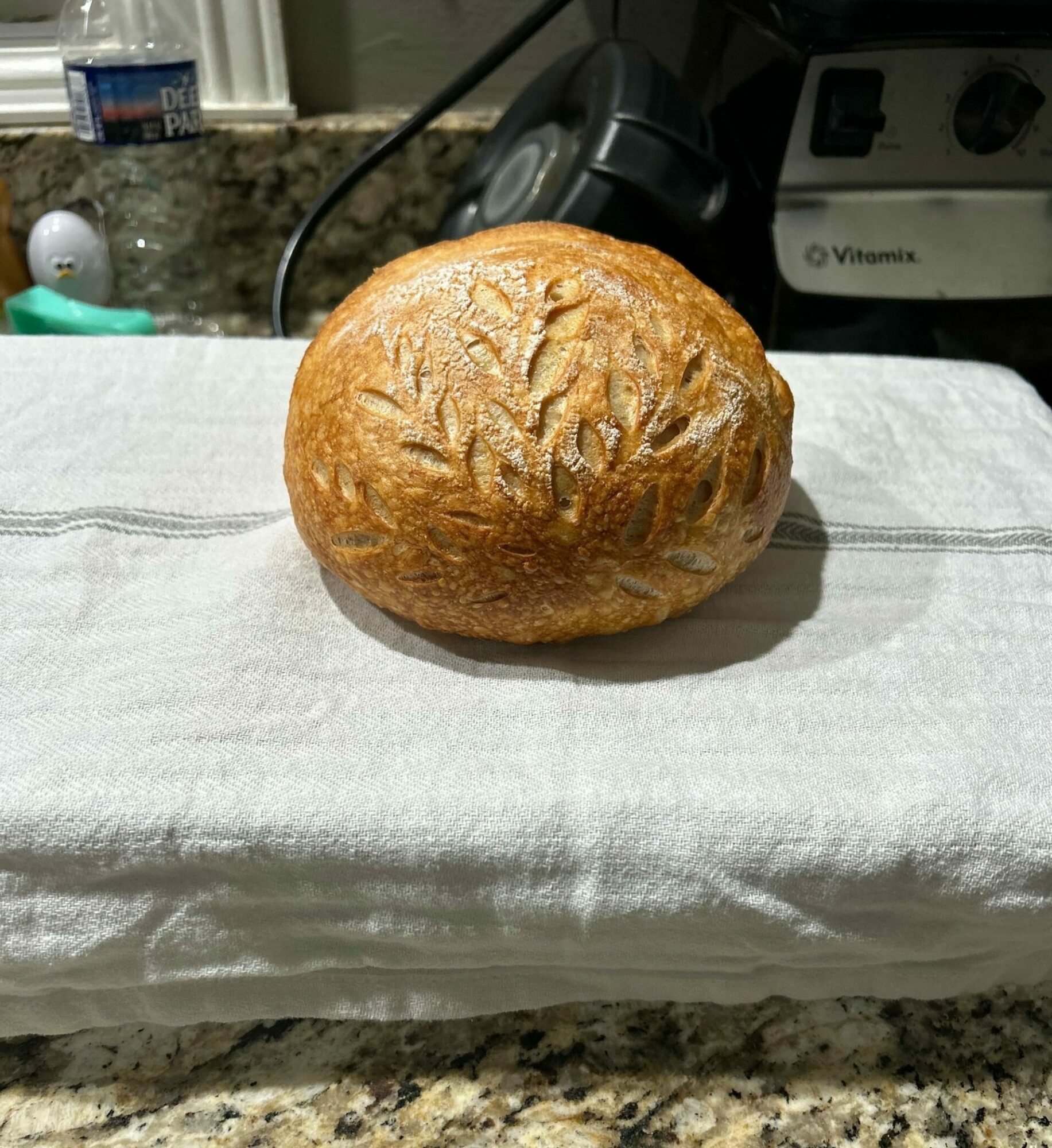 Round loaf of bread on a white cloth on a kitchen countertop.