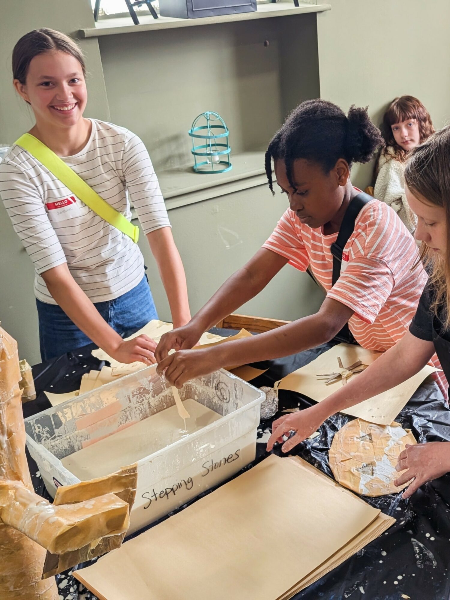 Group of children working together on a science experiment with a large container and paper towels.