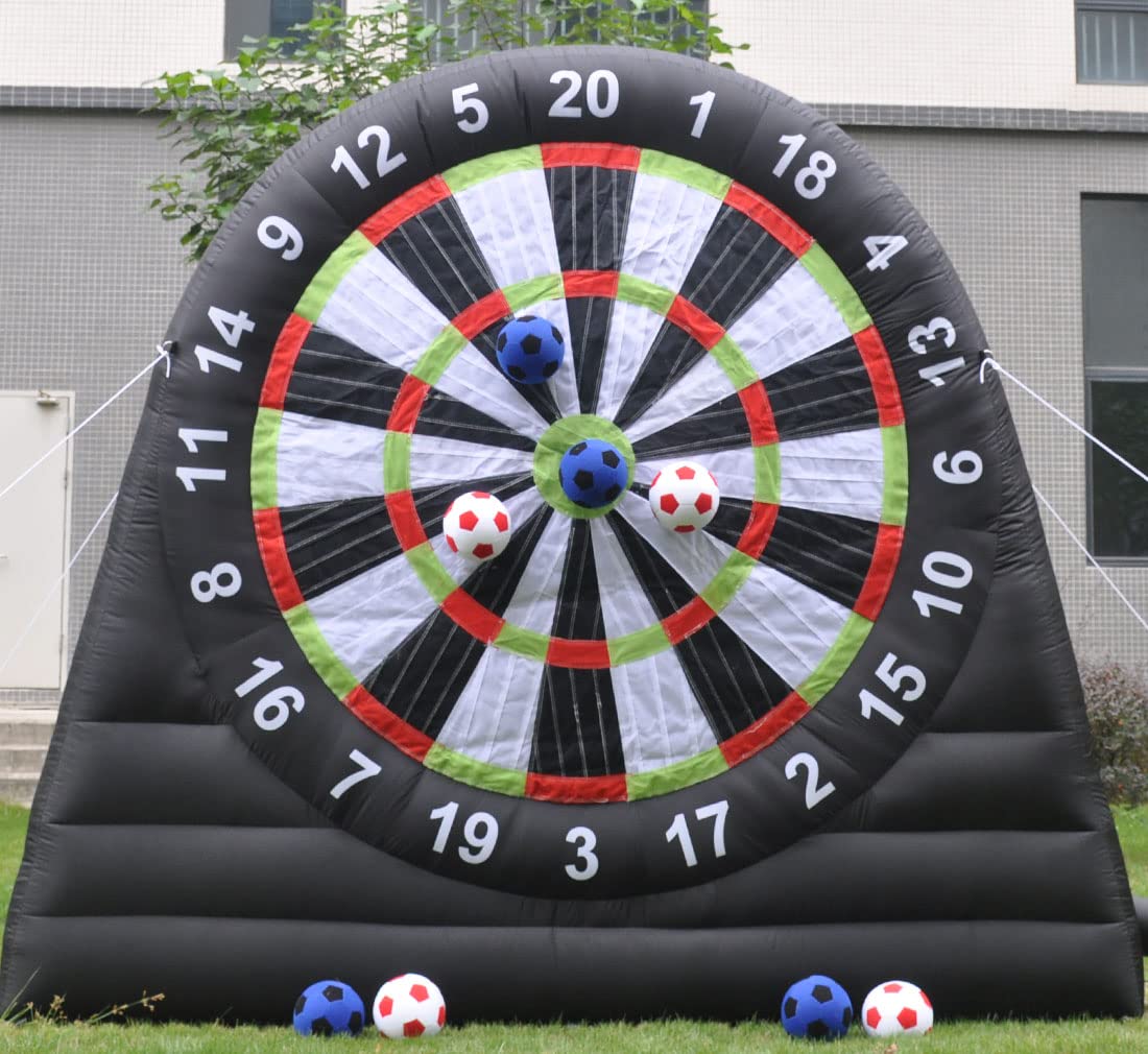 Inflatable dartboard with soccer balls and plush balls attached, set outdoors on grass with a building in the background.