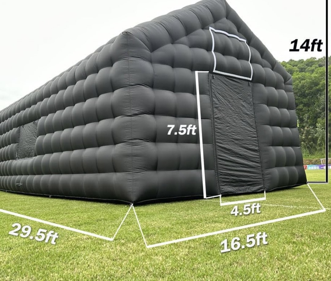 Inflatable black structure with measurements: 14ft high, 7.5ft wide, 4.5ft door, on grass field.