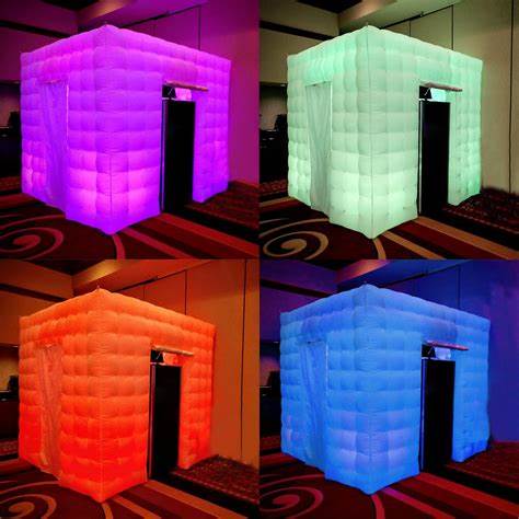 Inflatable cube with colorful LED lights, glowing in purple, green, orange, and blue, placed indoors on a patterned carpet.