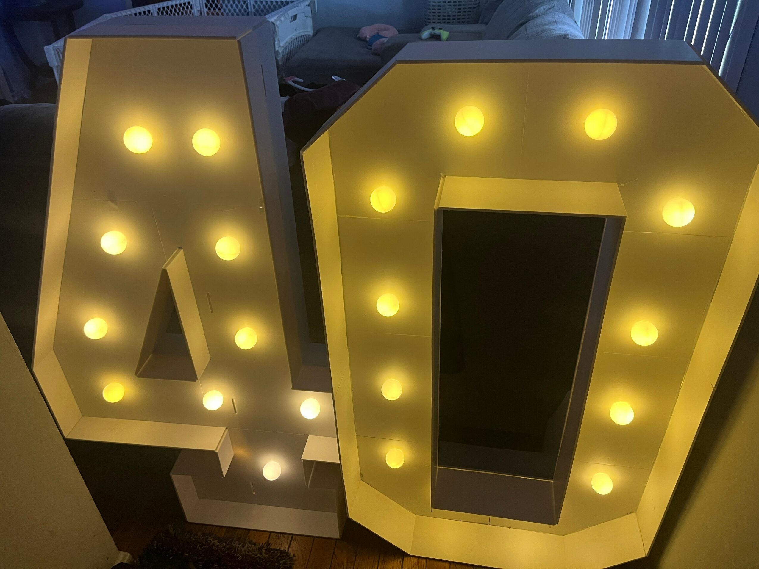 Two large illuminated marquee letters, one with the number 4 and the other with the number 0, lit with yellow bulbs.
