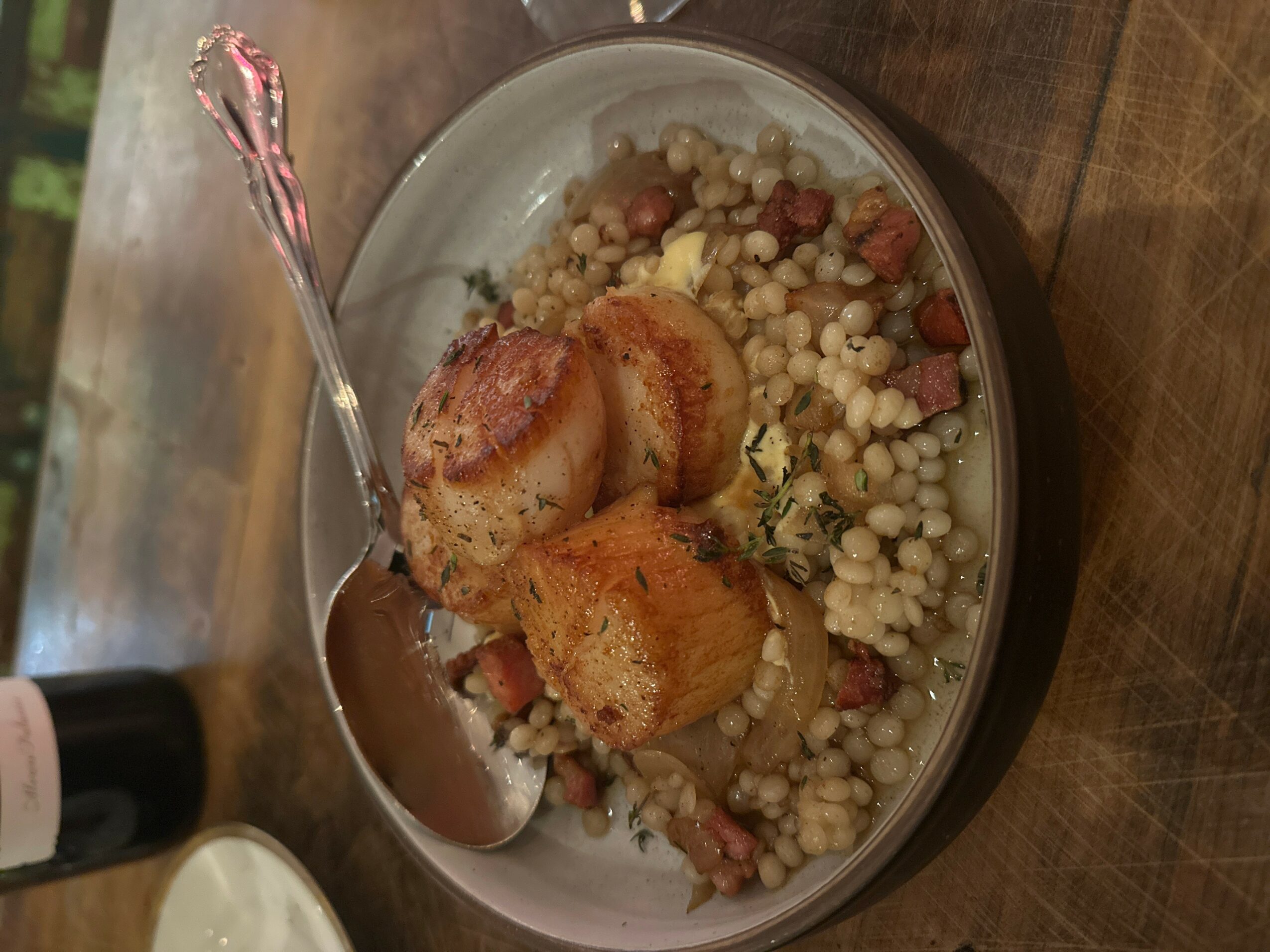 Bowl with two pieces of breaded food and a grain-based dish with beans, on a wooden surface.