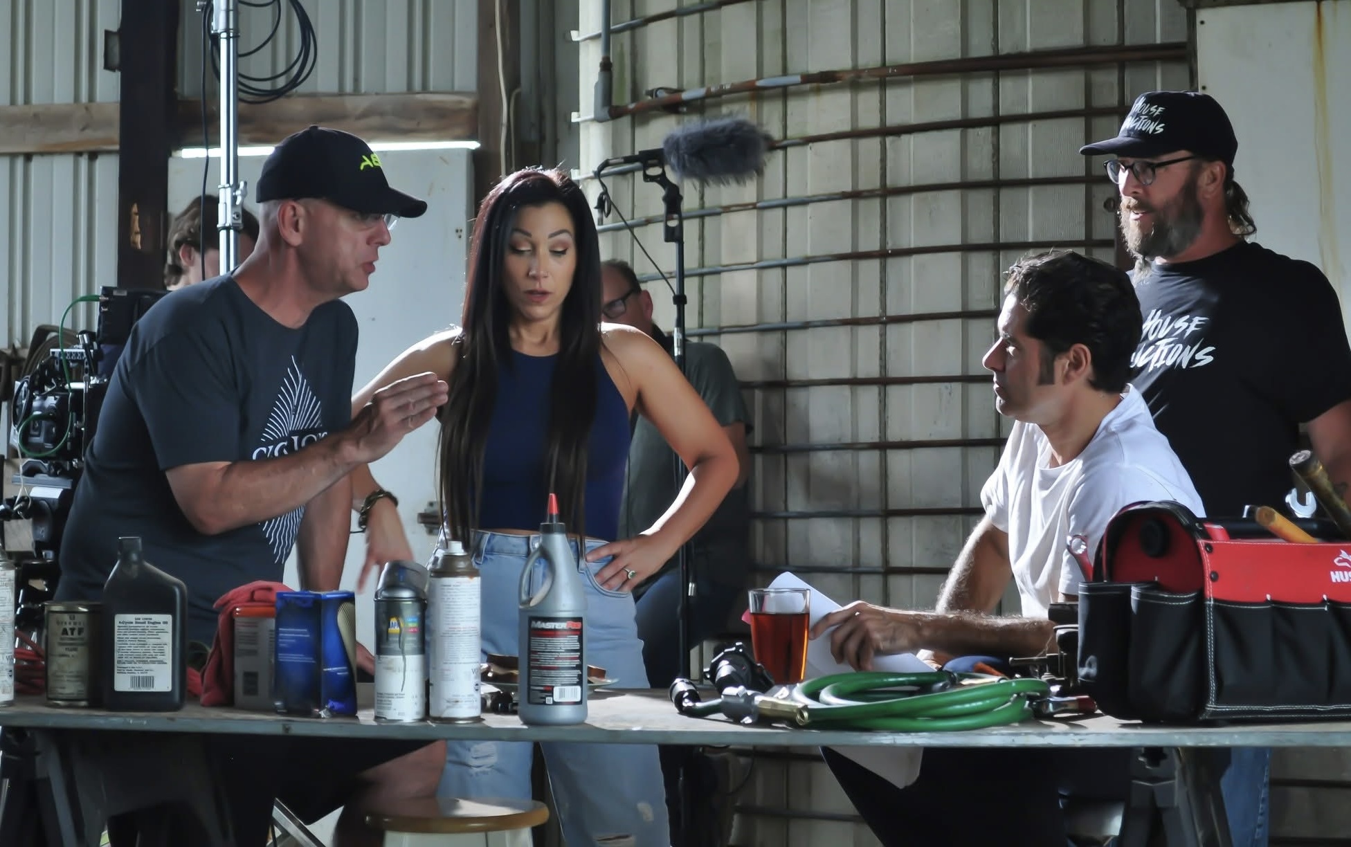 Four people on a film set, with equipment and drinks, engaged in conversation indoors.
