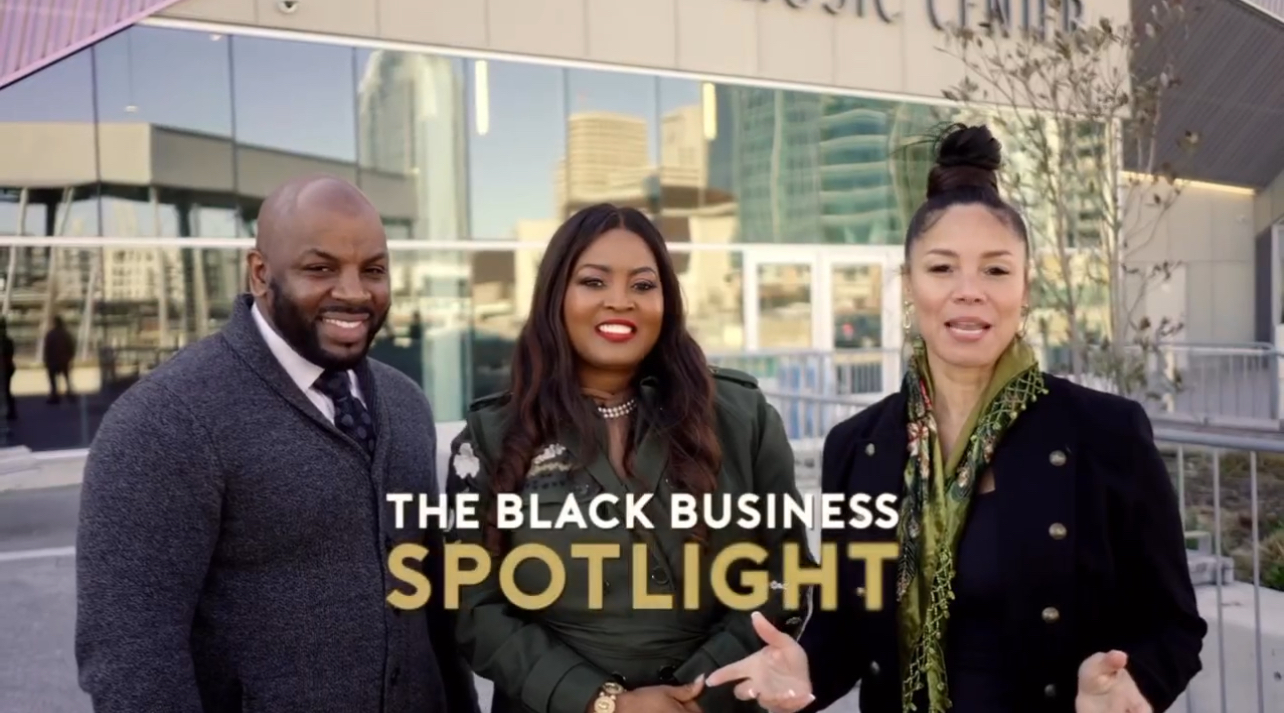 Three people standing outdoors in front of a glass building, smiling, with text overlay reading 'The Black Business Spotlight'.