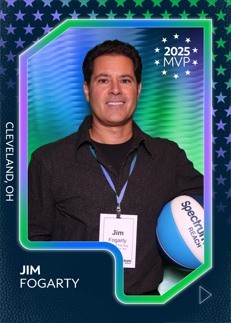 Man smiling wearing a name badge and holding a blue and white volleyball, with a background of stars and green and blue colors.