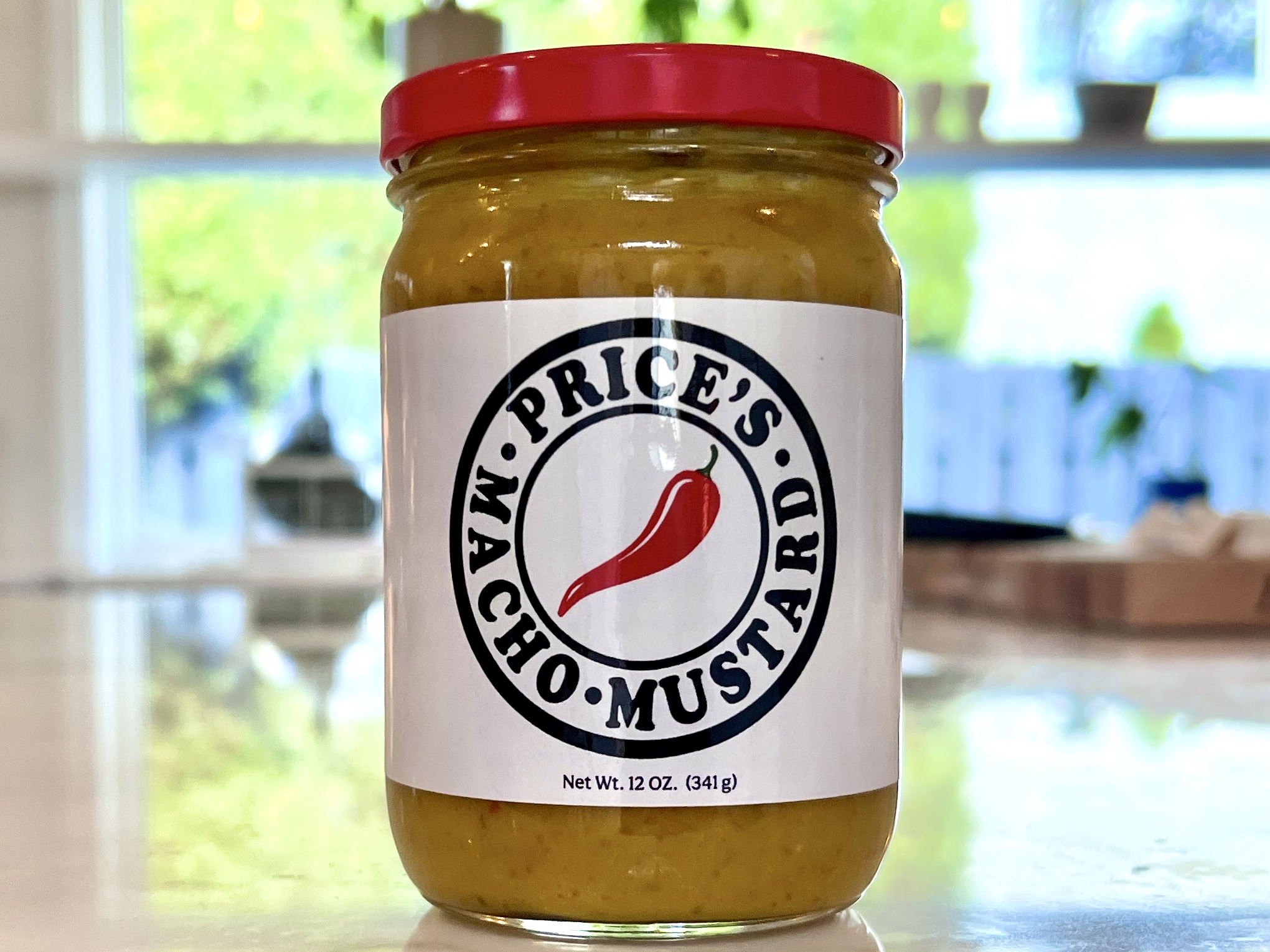 Jar of mustard with a red lid and a label featuring a chili pepper and the words 'Price's Macho Mustard'.