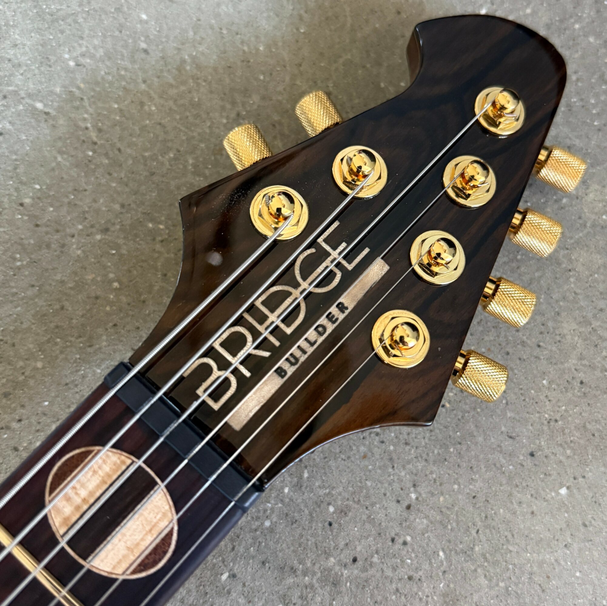 Close-up of a black guitar headstock with gold tuning pegs and the brand name 'PRS' and model 'Builder' visible.