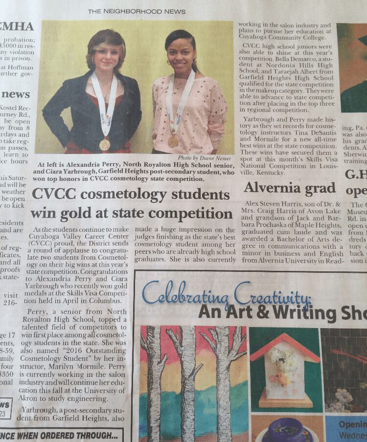 Two students wearing medals and smiling, standing in front of a green background, celebrating achievement.