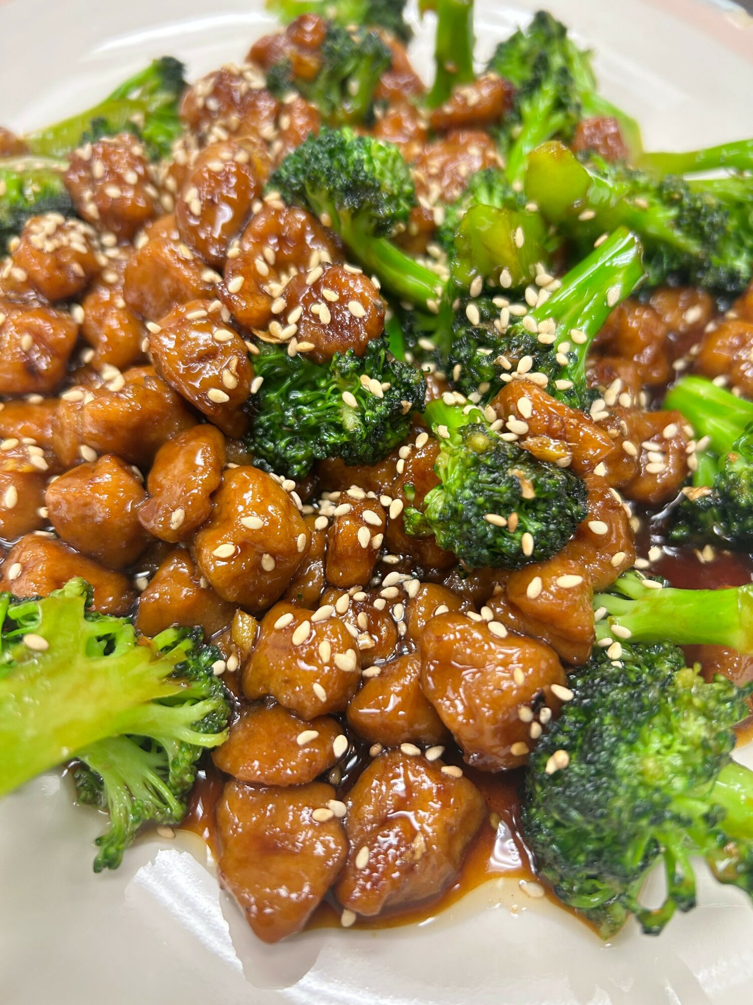 Stir-fried broccoli and chicken with sesame seeds on a white plate.