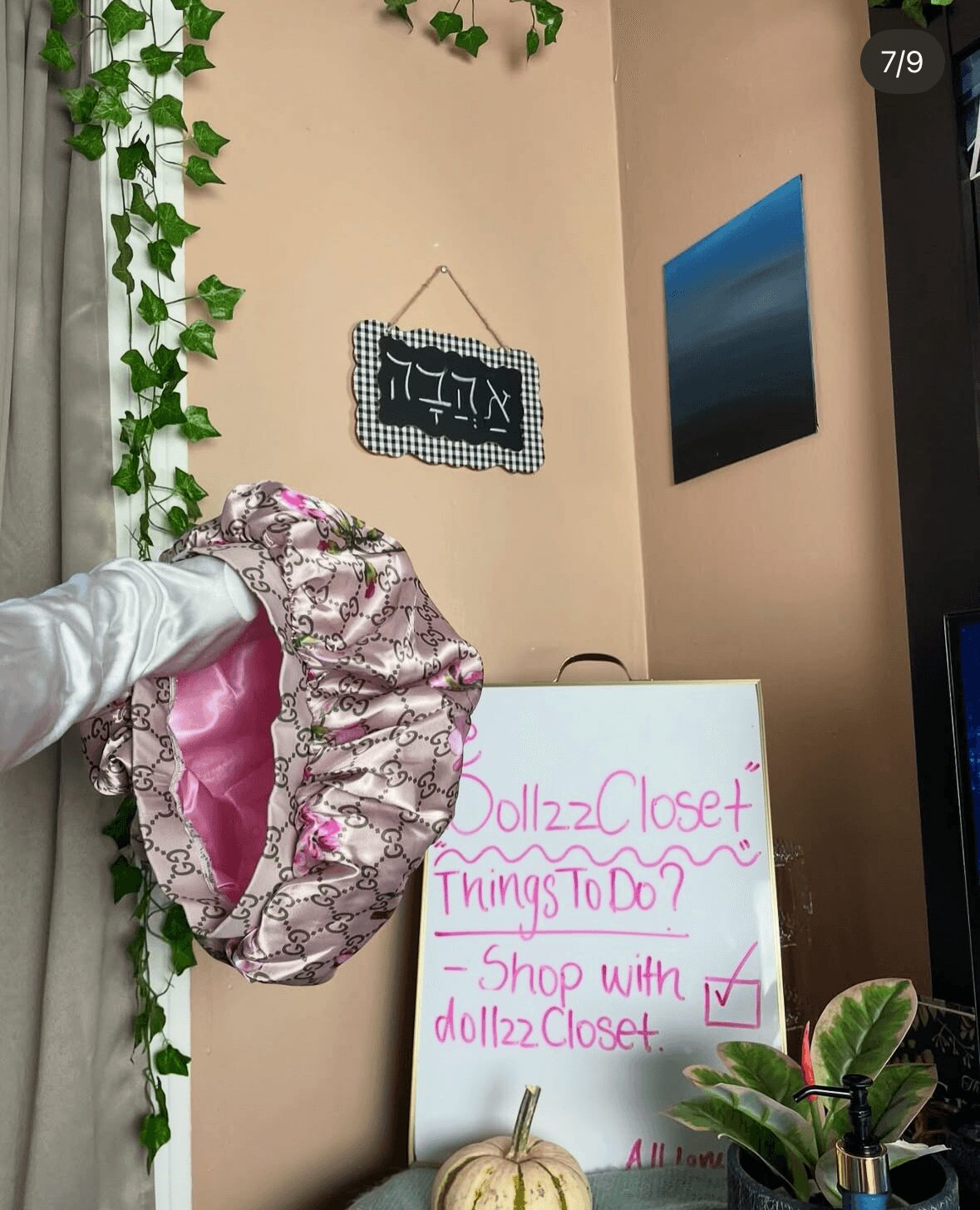 Decorated wall with a hanging sign, a whiteboard with to-do list, and a plant on a shelf.