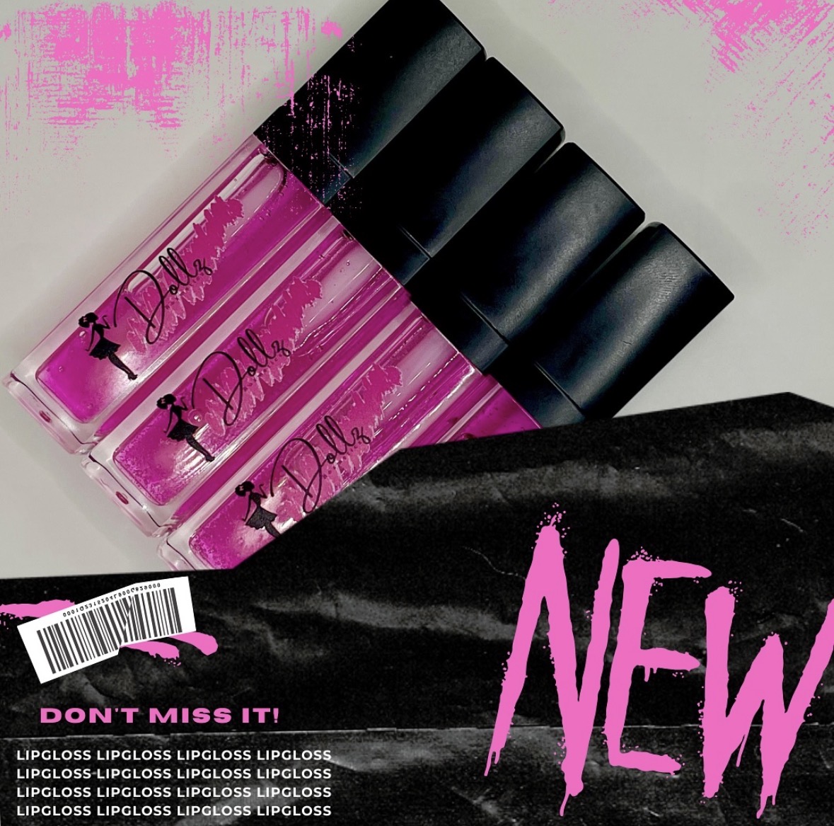 Four pink and black lip gloss tubes with a black and pink packaging, partially covered by black fabric with pink text.