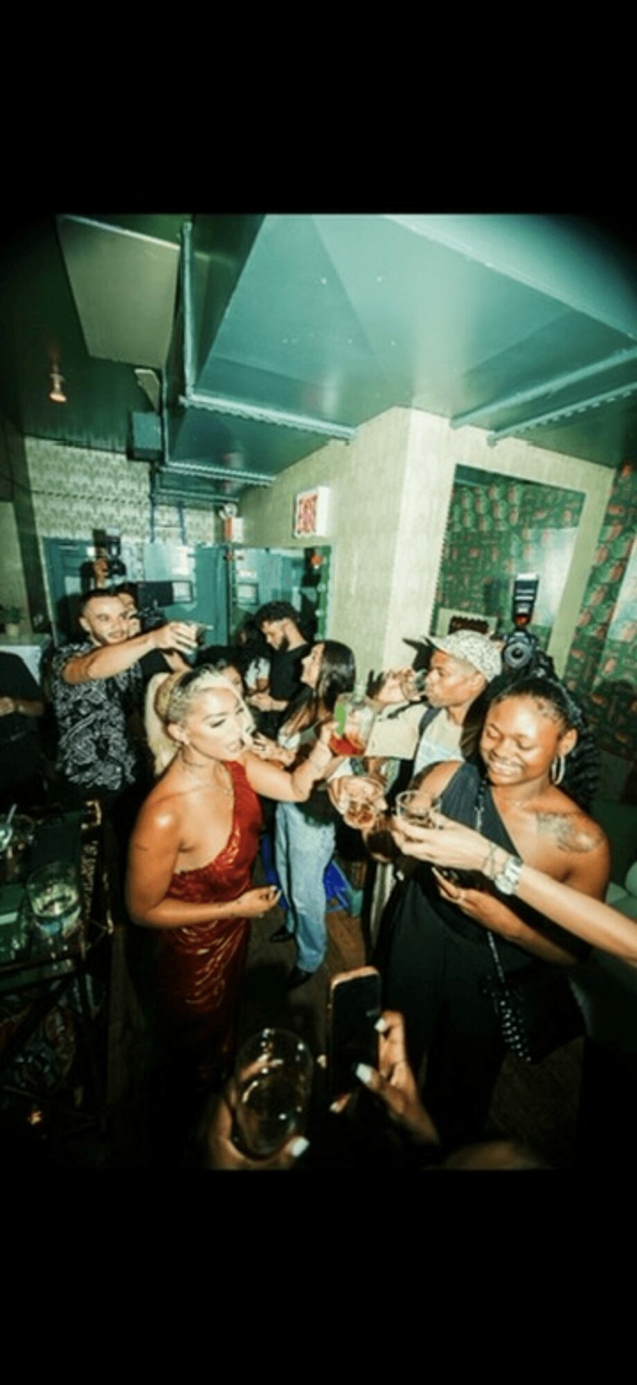 Group of women celebrating with drinks in a lively bar, smiling and enjoying each other's company.