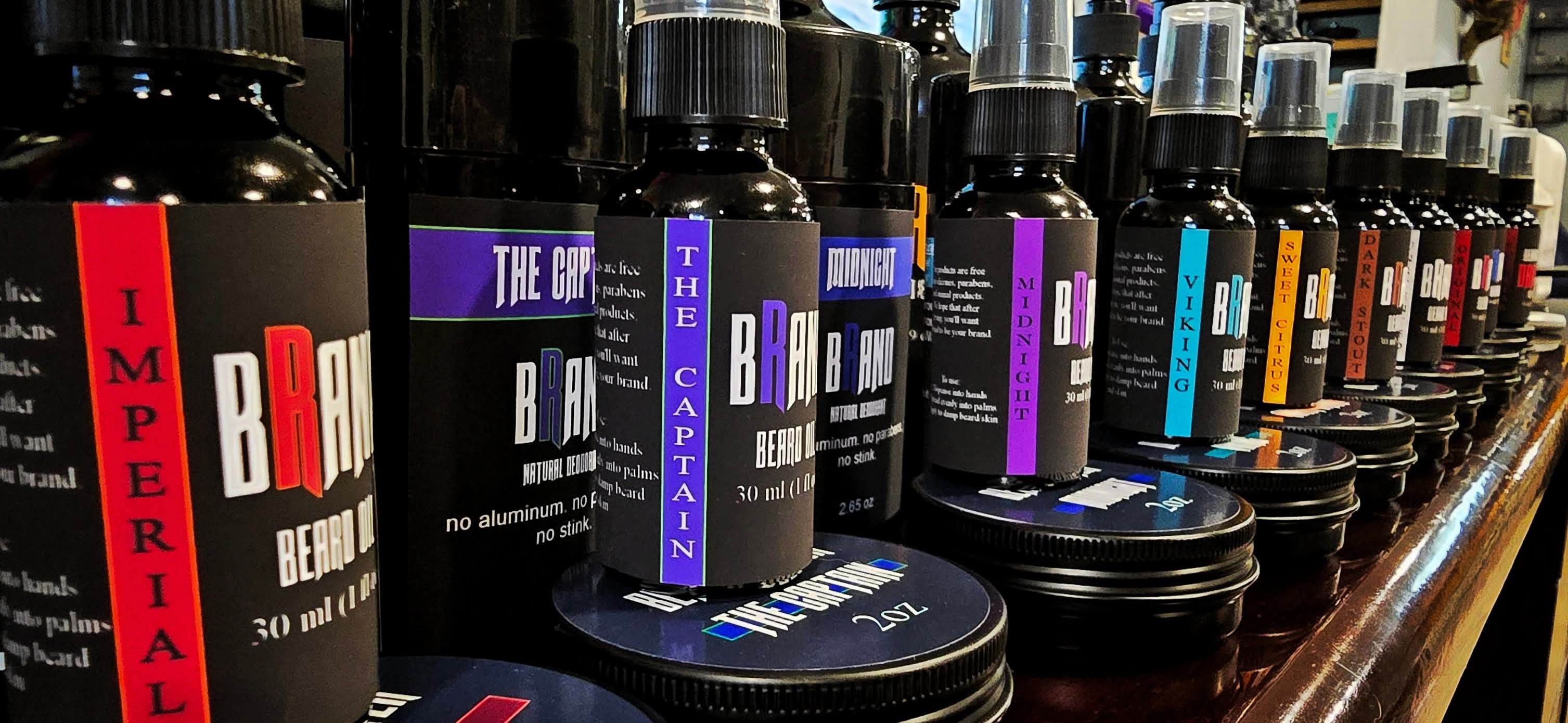 Shelf with various black bottles and containers, some with purple and red labels, arranged in a row.