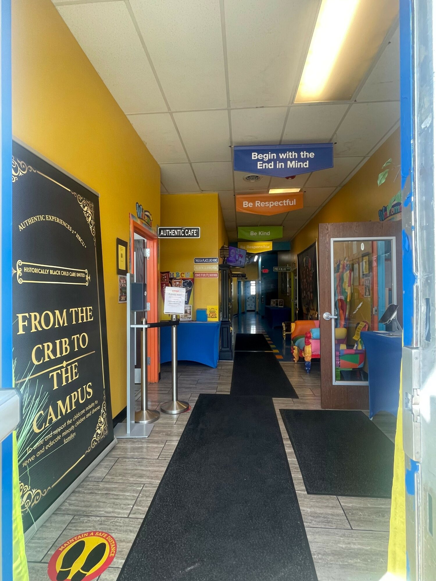 View of a store entrance with yellow and black walls, a black mat, and a sign for a credit card promotion.