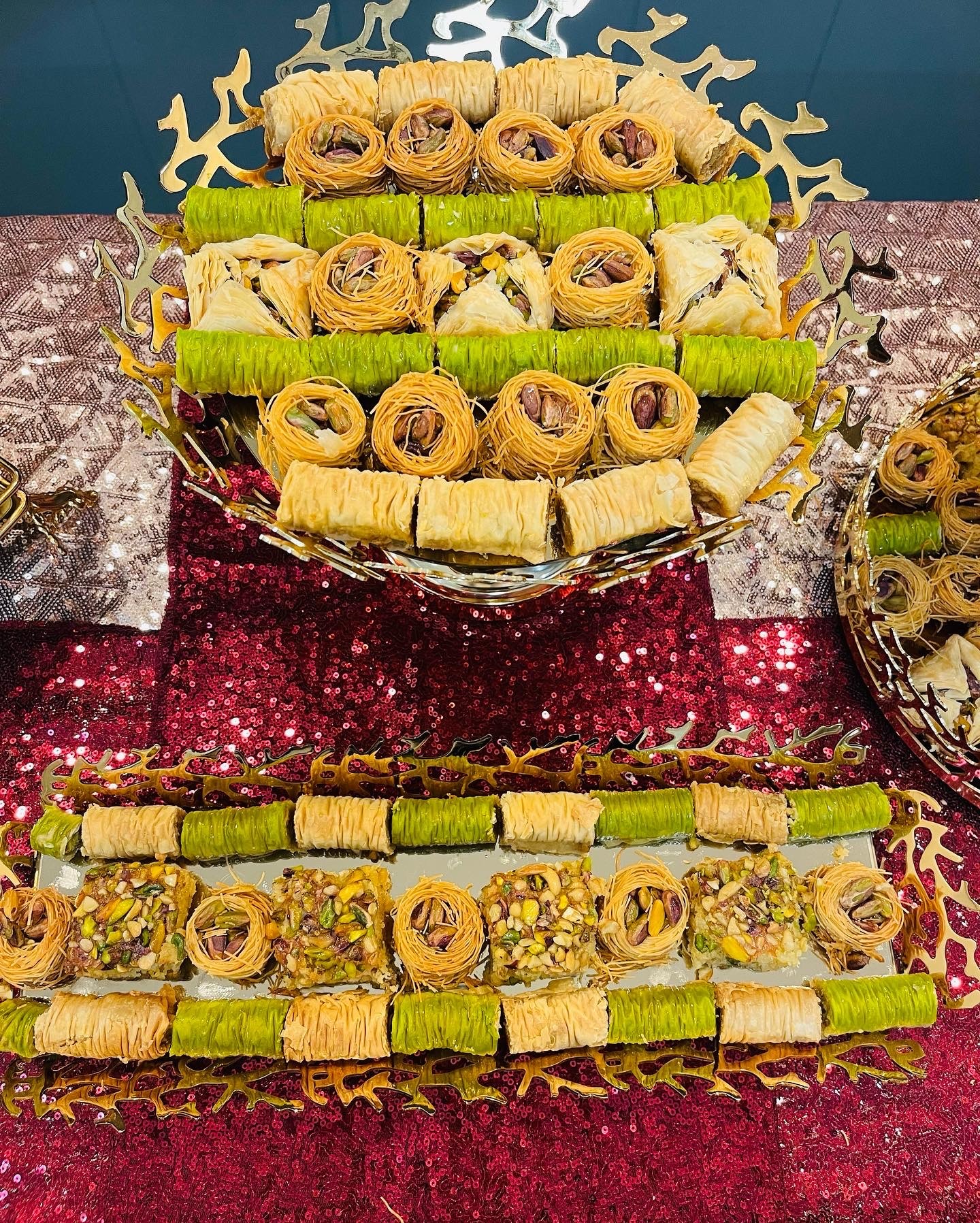 Tray of rolled pastries and sliced rolls on a table with decorative cloth, arranged in rows, with additional pastries on the side.