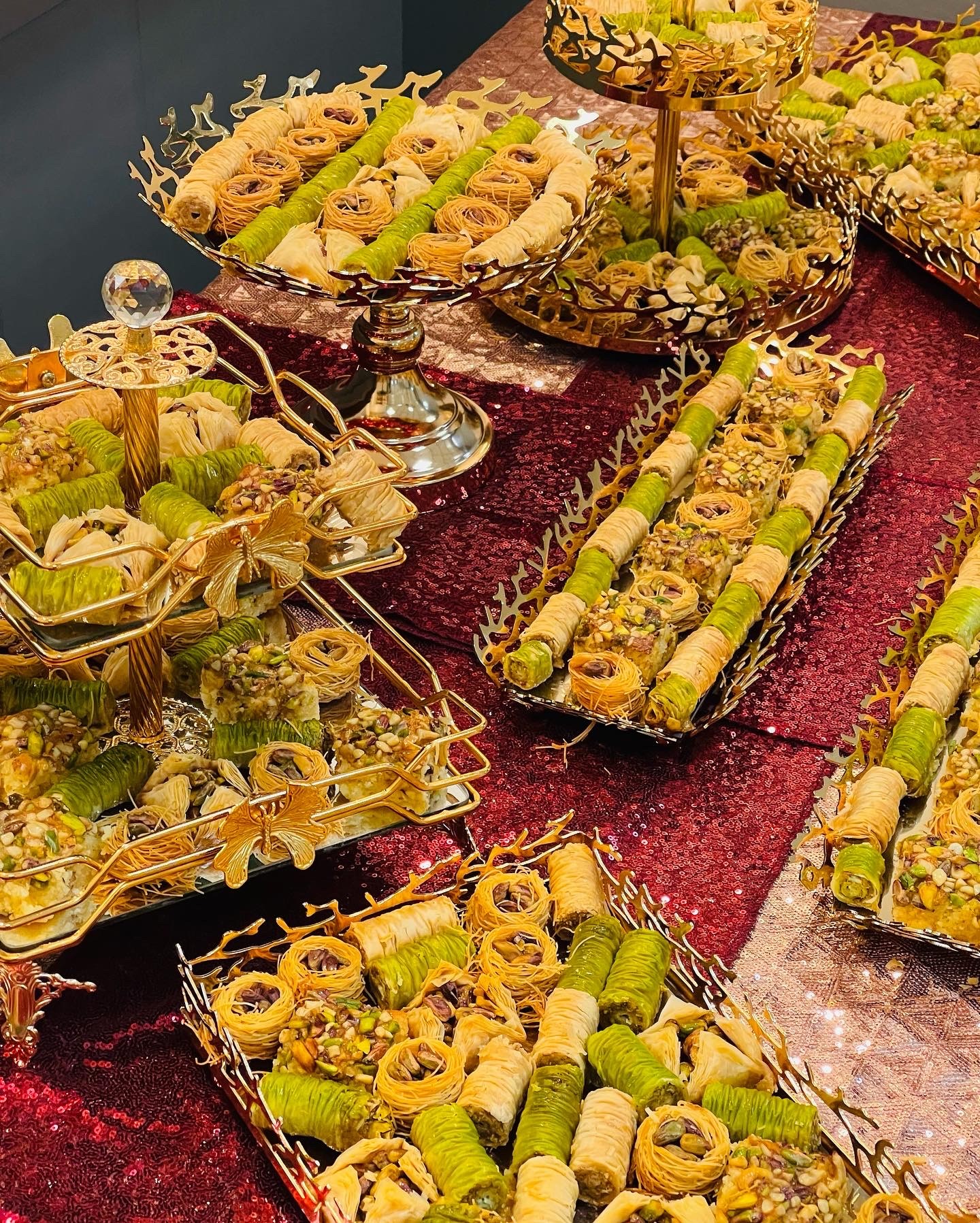 Assorted rolled and sliced appetizers on trays, with decorative elements, displayed on a table with a red cloth.