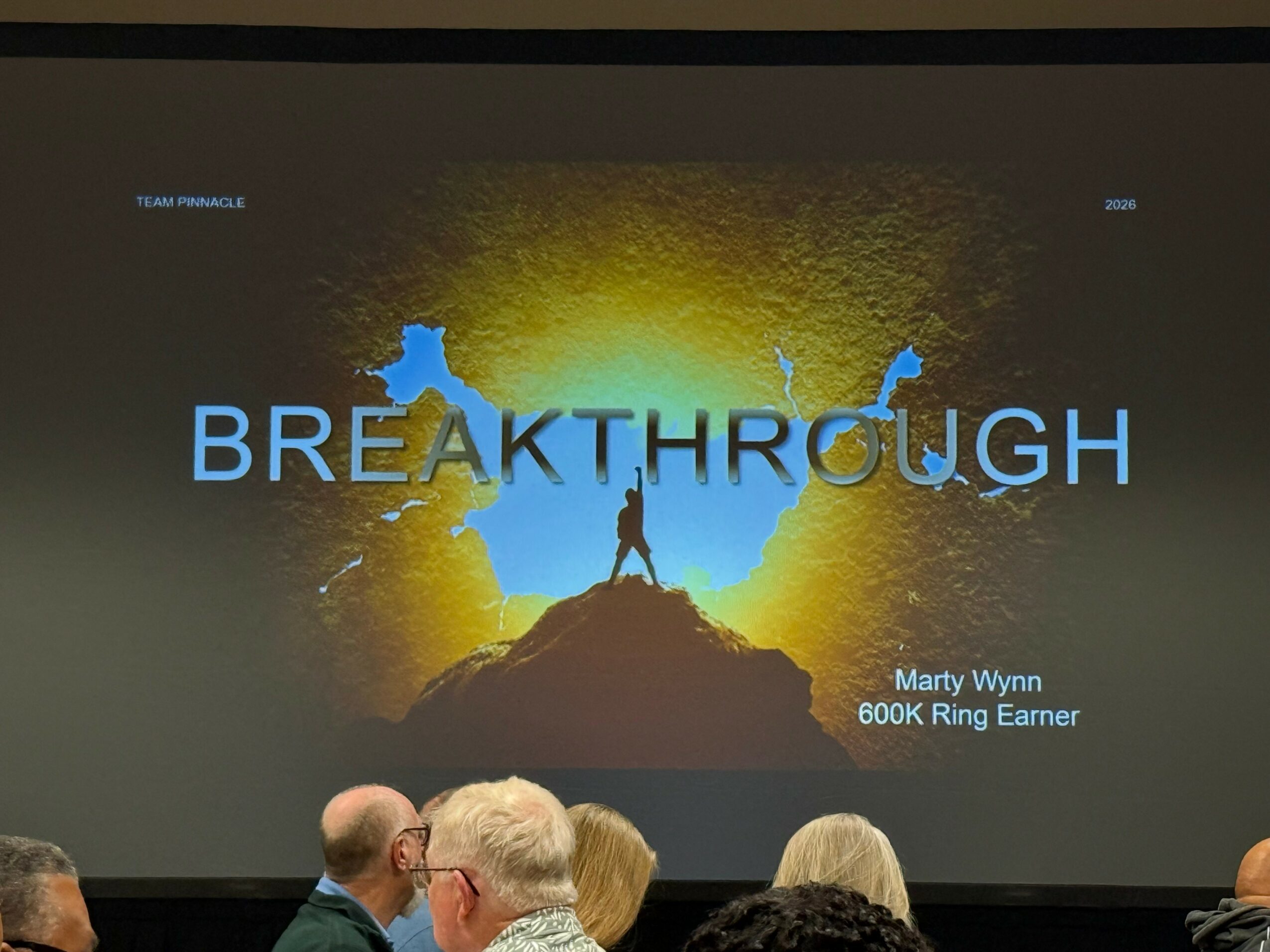 Presentation slide with the word 'BREAKTHROUGH' and a person standing on a mountain peak silhouette, with a bright background.
