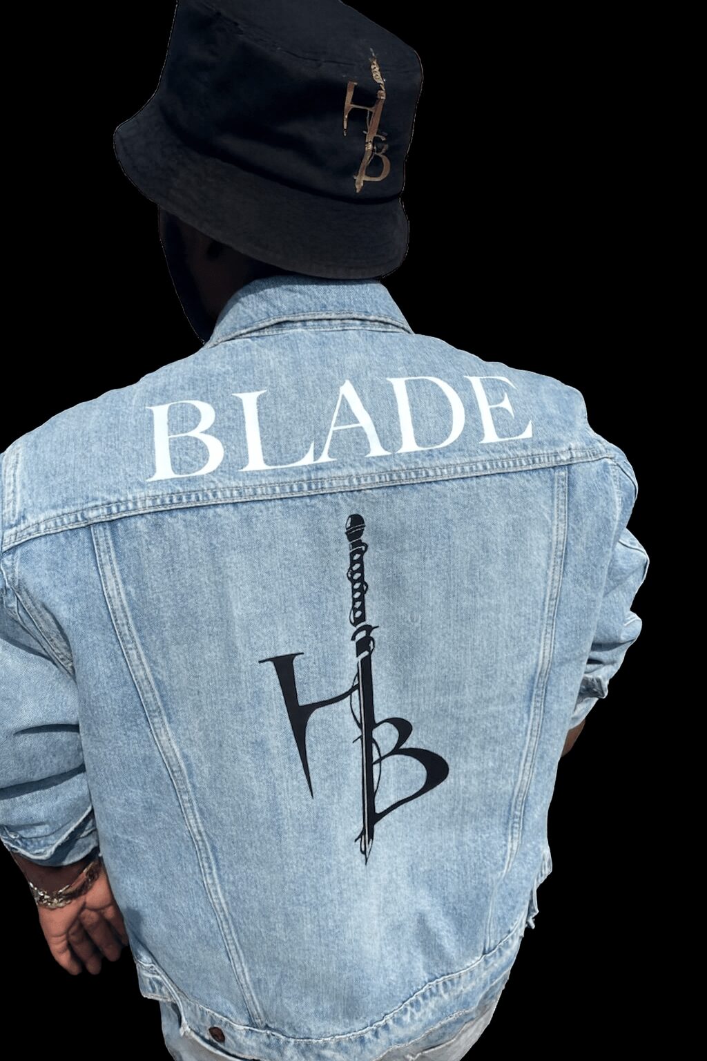 Person wearing a denim jacket with 'BLADE' and a logo on the back, and a dark bucket hat, facing away from the camera.