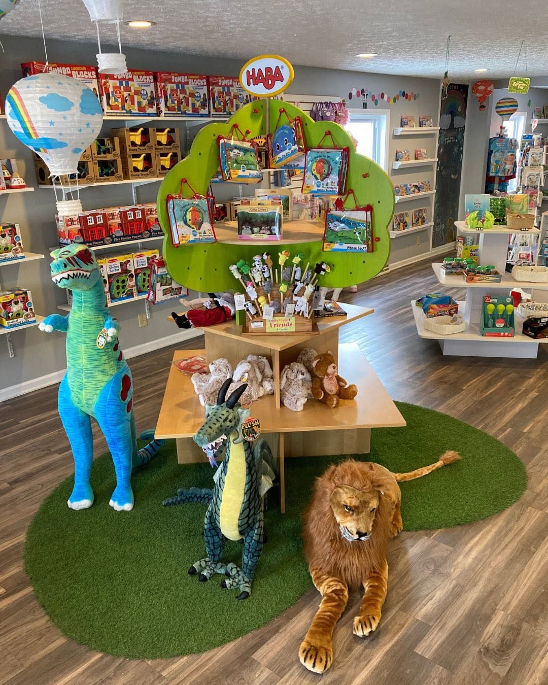 Toy store display with plush animals, a green tree-shaped shelf, and shelves of toys in the background.
