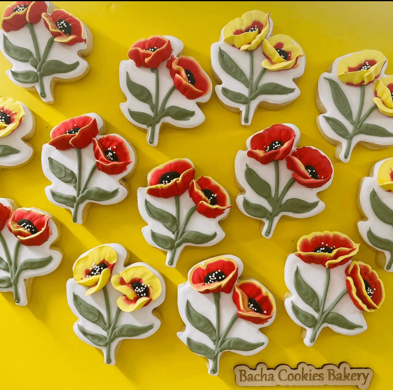 Cookies shaped like flowers with red and yellow petals and green leaves on a yellow background.
