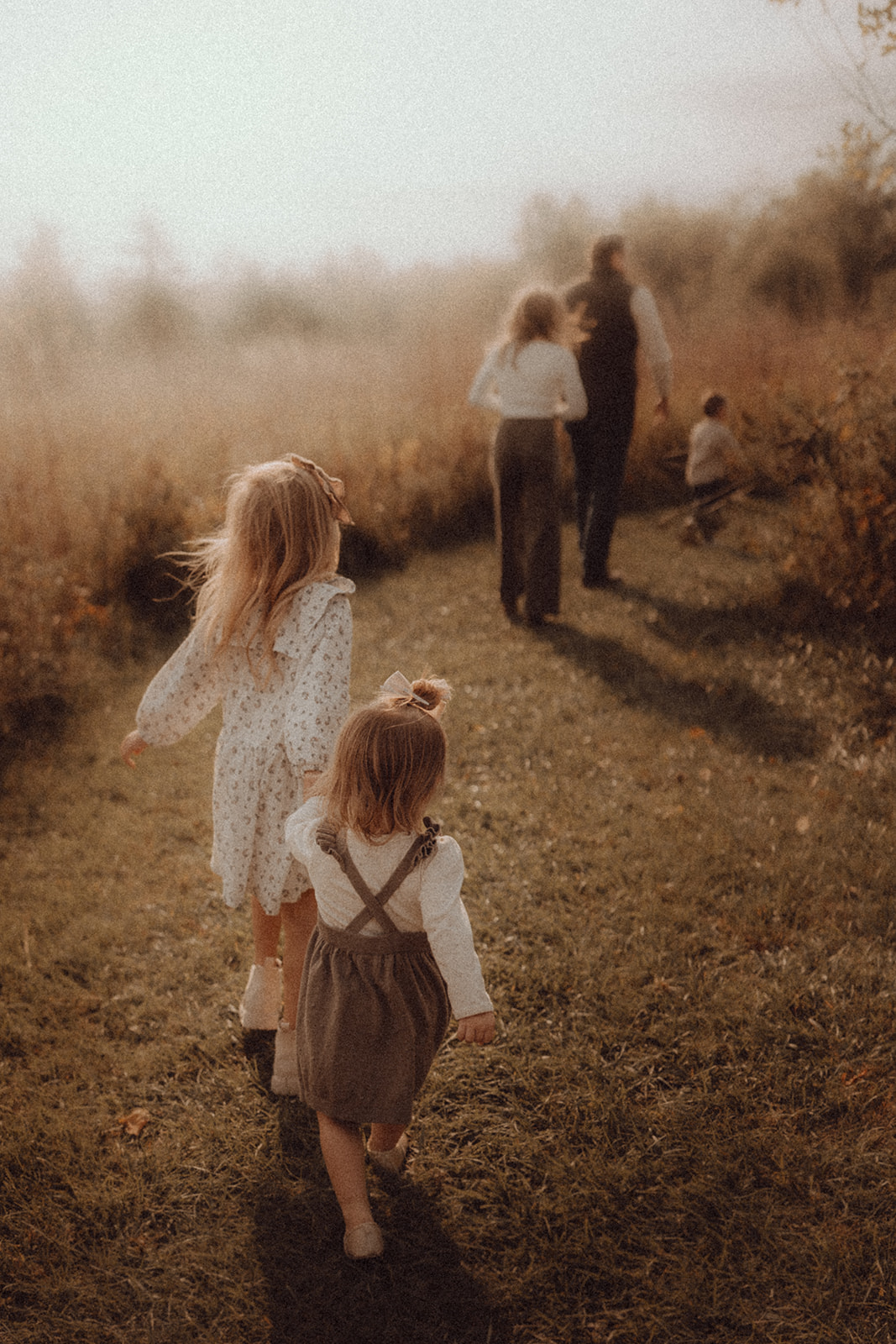 Children walking along a grassy path with adults in the background, in a natural outdoor setting during daytime.