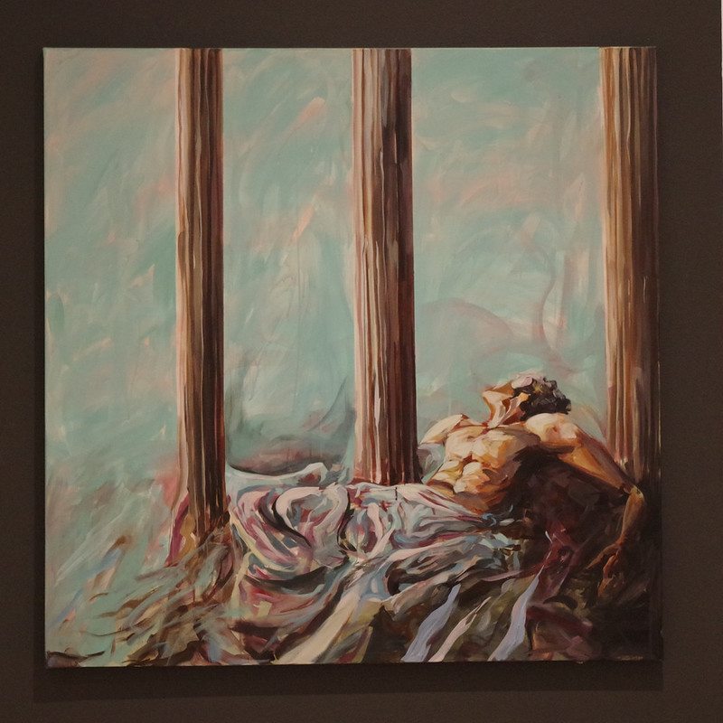 Painting of three vertical wooden columns with fabric and rocks on the ground, against a light blue background.