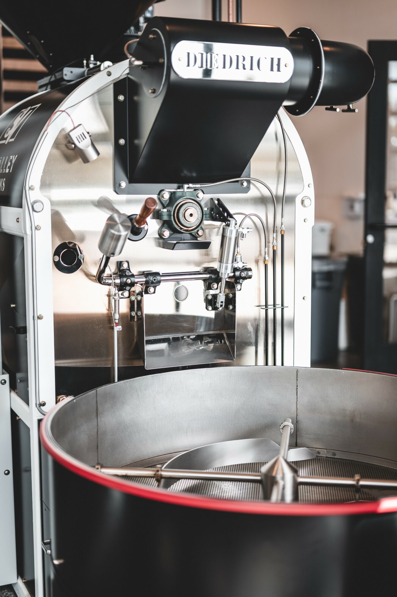 Close-up of a coffee roasting machine with a large metal drum and control panel.