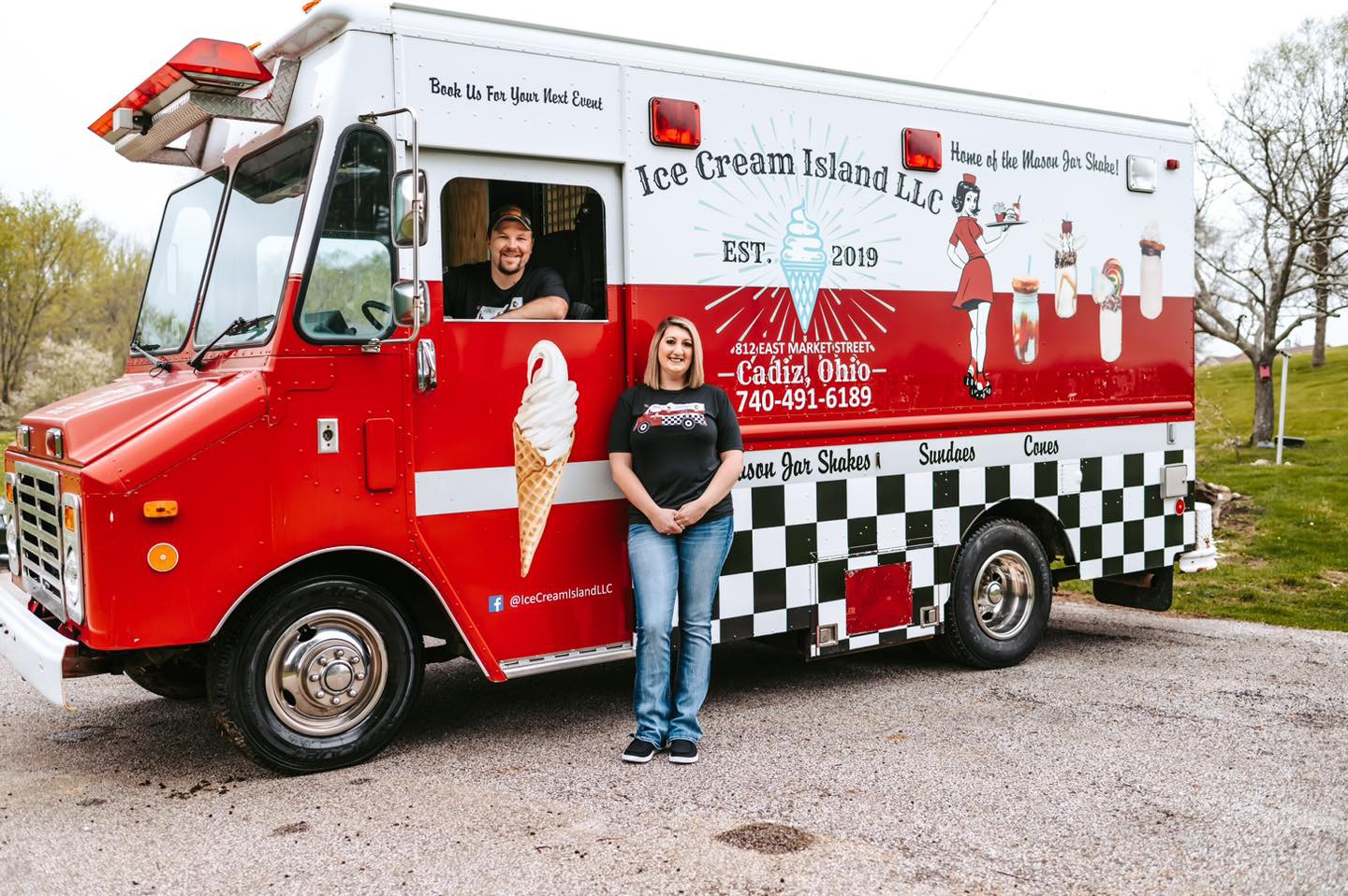 Person standing in front of ice cream truck with ice cream cone graphic, trees, and grass in background.