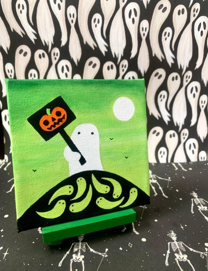 Halloween-themed artwork with a ghost holding a sign, a full moon, and a green landscape, against a ghost pattern background.