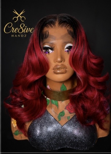 Bust of a woman with long, wavy red hair, makeup, and a glittery top, against a black background.