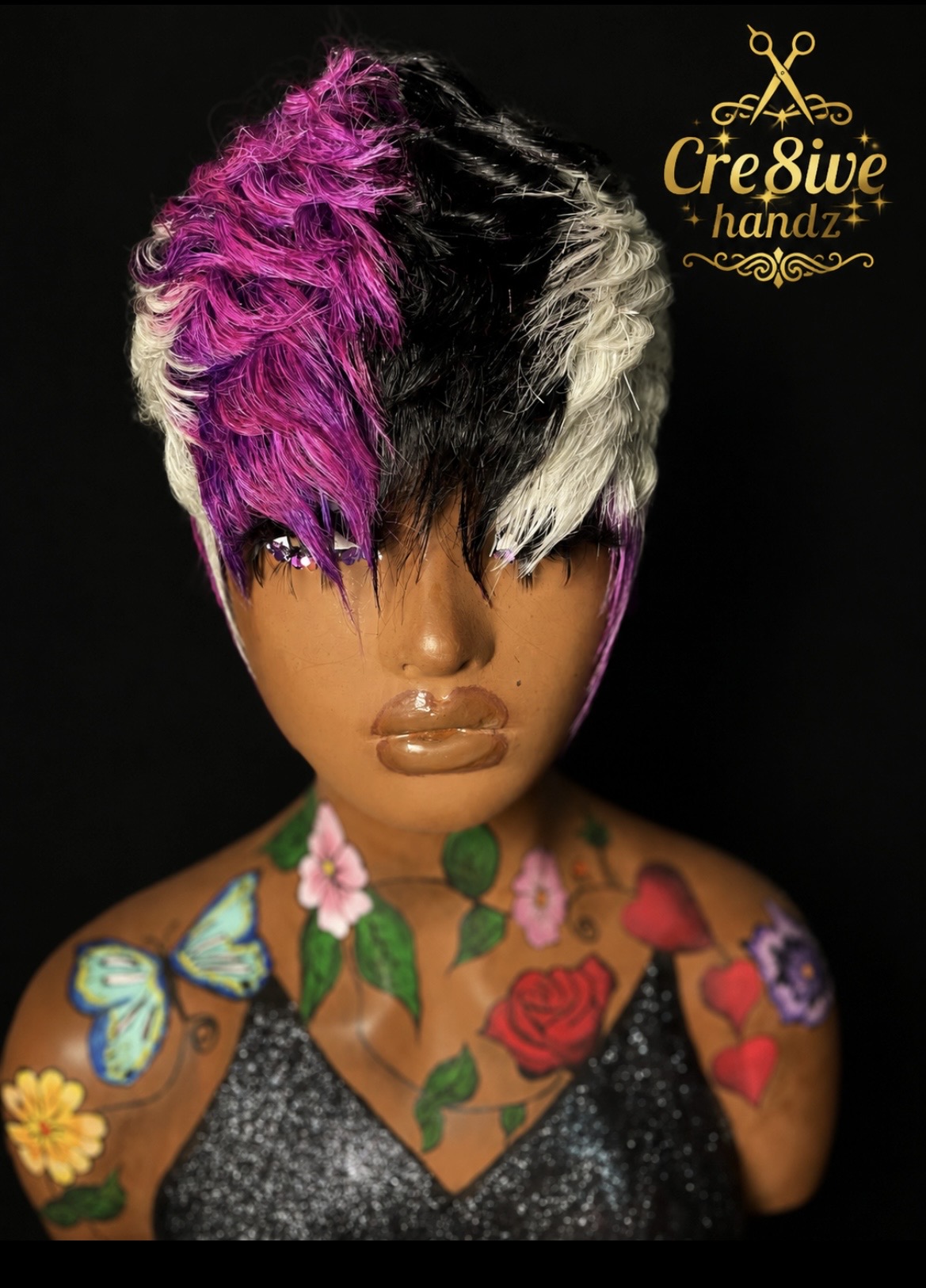 Mannequin with colorful hairstyle, tattoos, and makeup, against a black background. Text reads 'Cre8ive handz' in the top right corner.