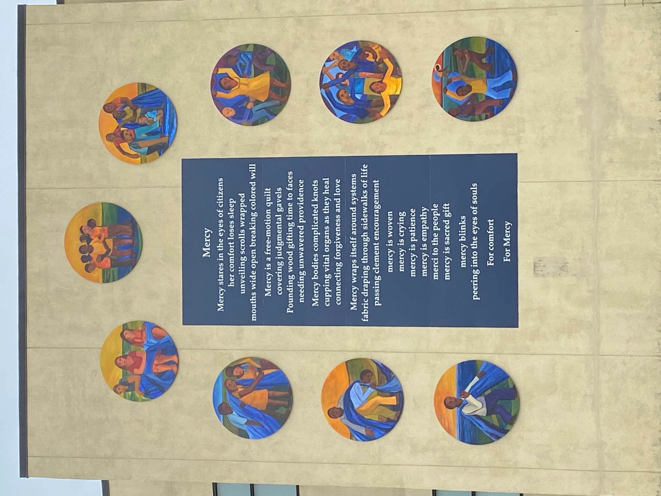 Wall display with ten circular illustrations surrounding a blue informational panel, all rotated 90 degrees clockwise.