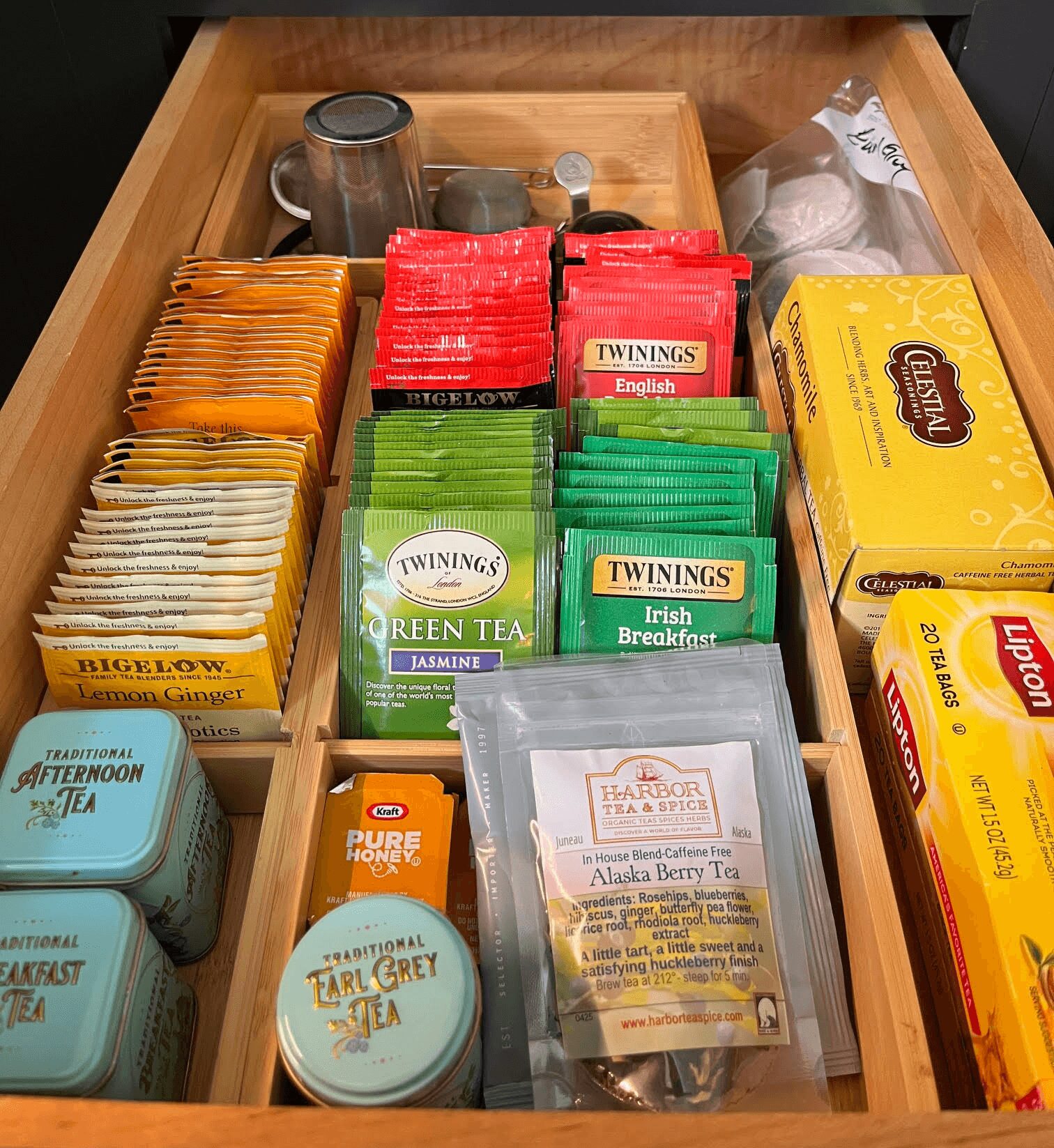 Open drawer with various tea boxes and packets, including Twinings, Lipton, and other brands, organized in sections.