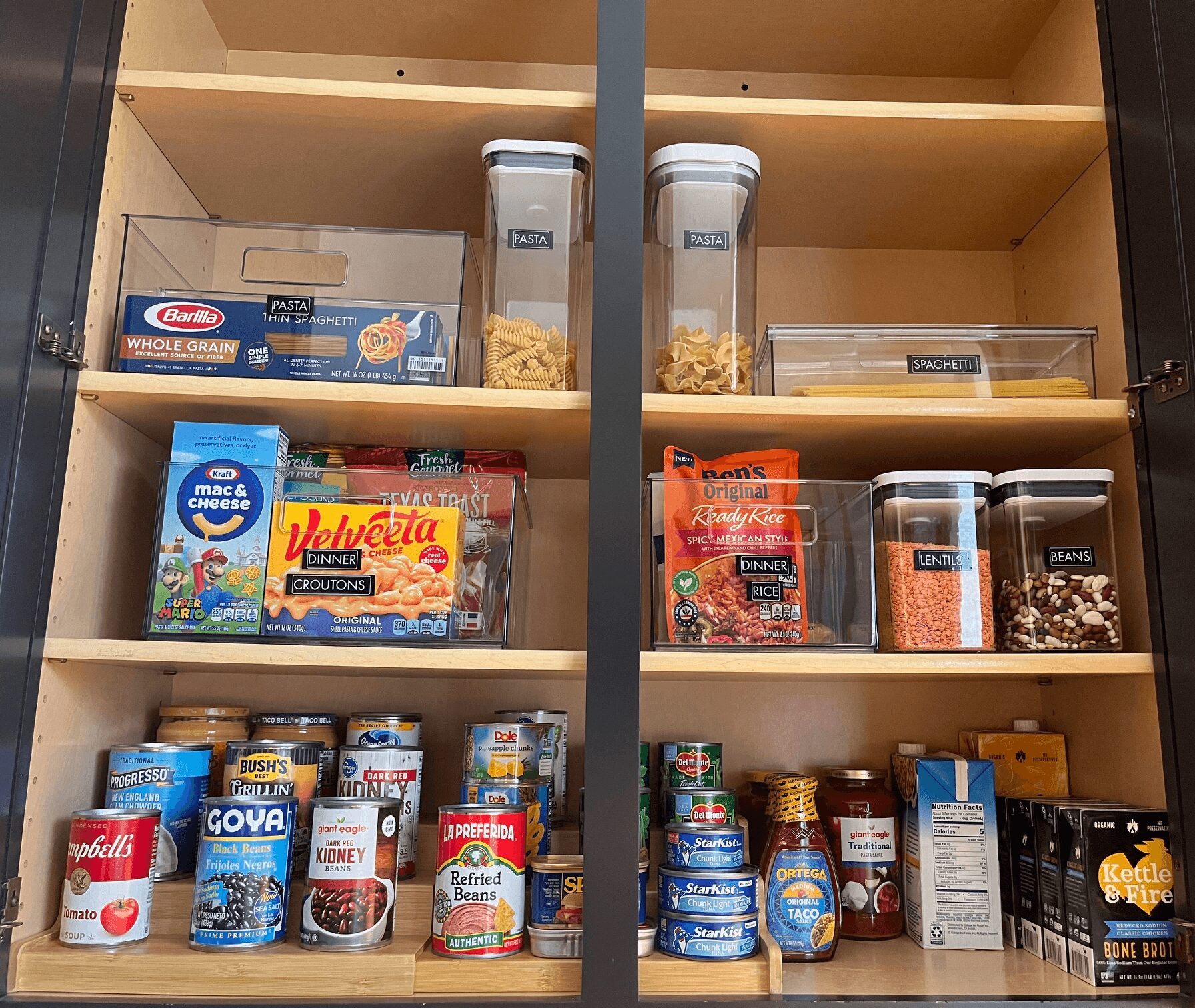 Pantry shelf with snacks, cereals, and canned goods organized in containers and boxes.